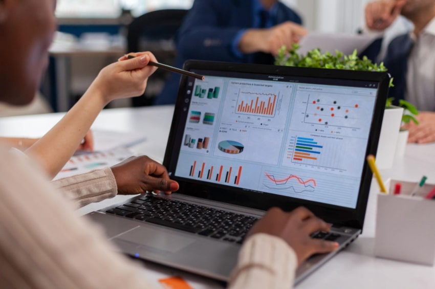 A group of people working together at a computer displaying statistics.