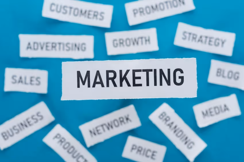 A collection of ripped pieces of paper with various words written on them. The word Marketing highli A collection of ripped pieces of paper with various words written on them. The word Marketing highli