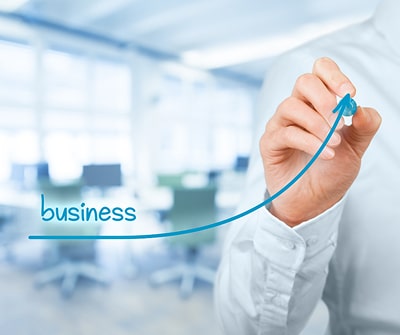 A man’s hand drawing a progressive arrow with the word “business” at the beginning of the arrow. Sou