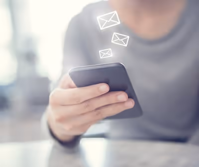 Image of someone on the phone, email icons emerging from the phone
