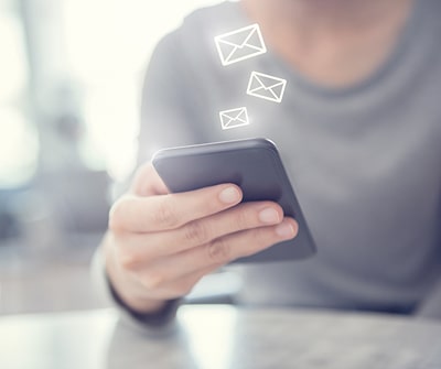 Image of someone on the phone, email icons emerging from the phone