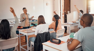 Students in a classroom raising their hands to ask questions