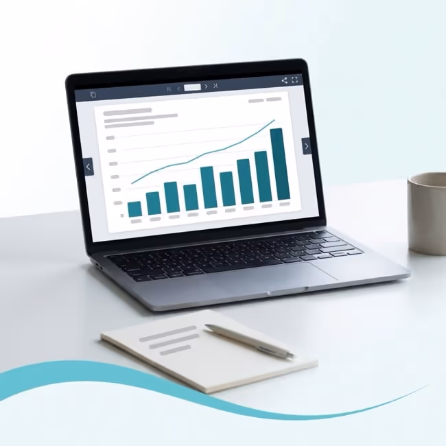 A laptop on a desk showing a chart with rising teal bars.