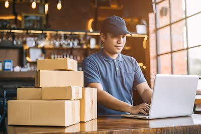 A man working on his laptop with packages beside him A man working on his laptop with packages beside him