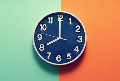 A clock in front of a green and orange background