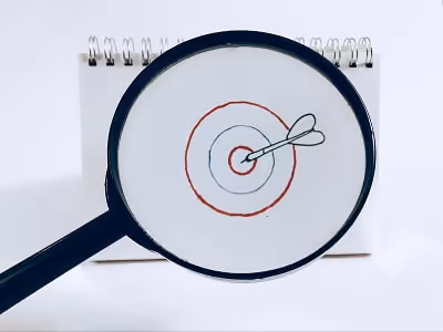 Magnifying glass focusing on a target drawn on paper Magnifying glass focusing on a target drawn on paper