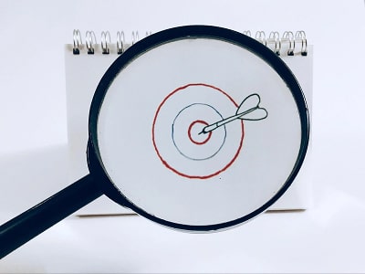 Magnifying glass focusing on a target drawn on paper