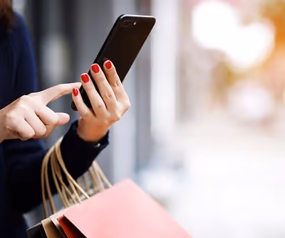 In-app shopping, person holding a phone and shopping bags