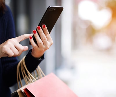 In-app shopping, person holding a phone and shopping bags