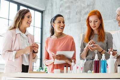 Three women testing and talking about cosmetic products