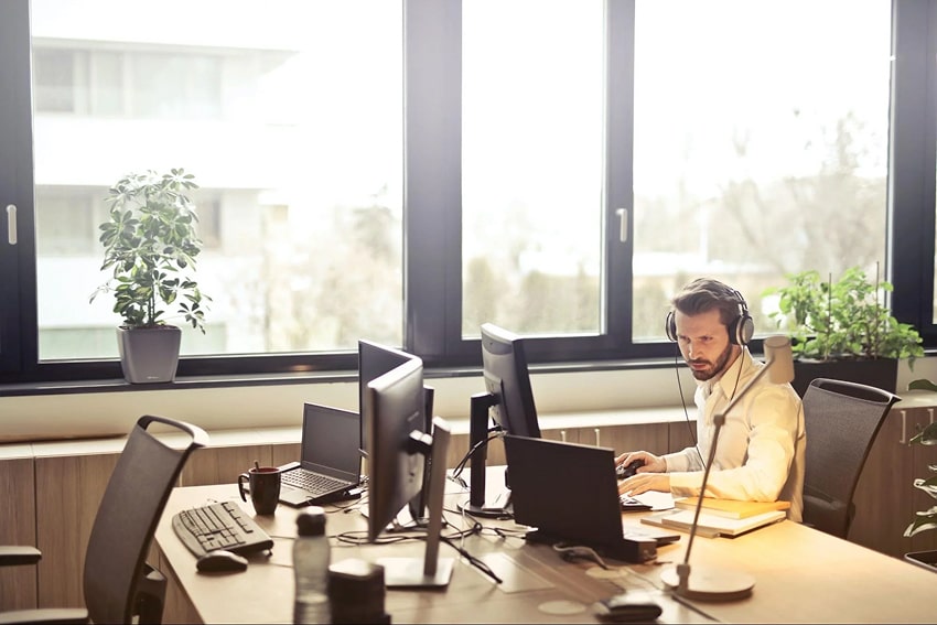 A man working on a computer in an office that has plants