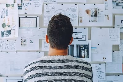 A man standing in front of a white board thinking about what tool to use for calculating revenue. A man standing in front of a white board thinking about what tool to use for calculating revenue.