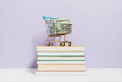 A shopping cart on the top of some books