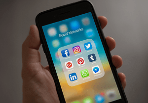Person holding an iPhone displaying different social media apps