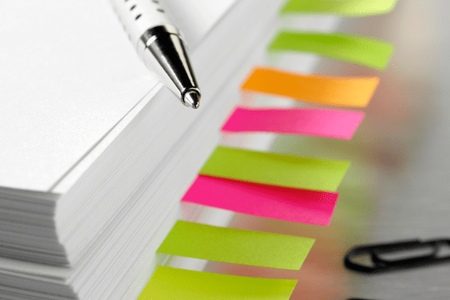 Photo of a stack of papers organized with colored sticky notes