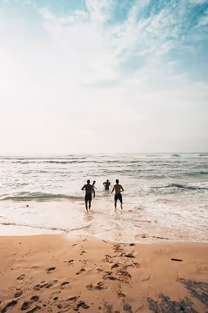 People running from the beach into clear blue water and having fun.