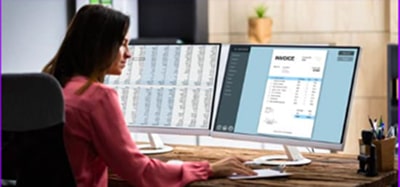A woman using an accounting software on her monitor screen.