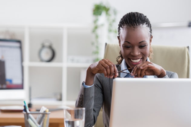 Woman sitting at a desk behind a computer, smiling