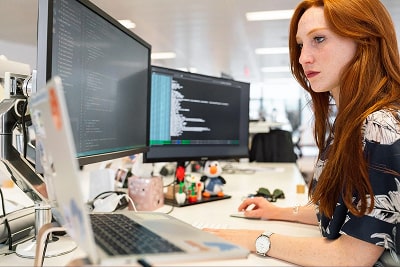A woman working on three screens.