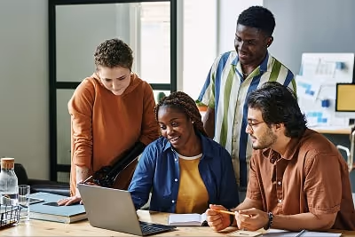 Group of people working together and looking at a laptop Group of people working together and looking at a laptop