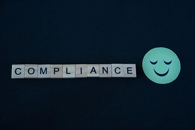 A picture with the word “compliance” and a smiley emoji.