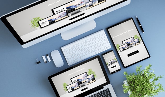 Multiple devices, including a laptop, phone, and iPad, are displayed on an office desk. The screens 