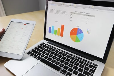A laptop displaying data, as well as an iPad showing a calendar.