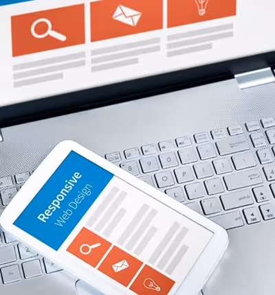 Close-up of a phone lying on a laptop keyboard. Both the phone and laptop screens display text that Close-up of a phone lying on a laptop keyboard. Both the phone and laptop screens display text that