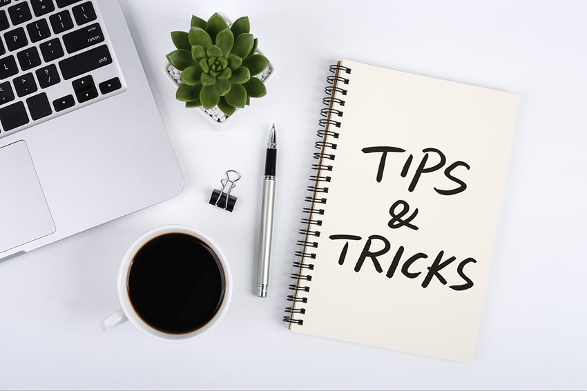 Several things on a desk, among which a notebook that states ''Tips and Tricks''
