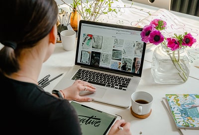 A woman from the back working on her laptop on visuals. 